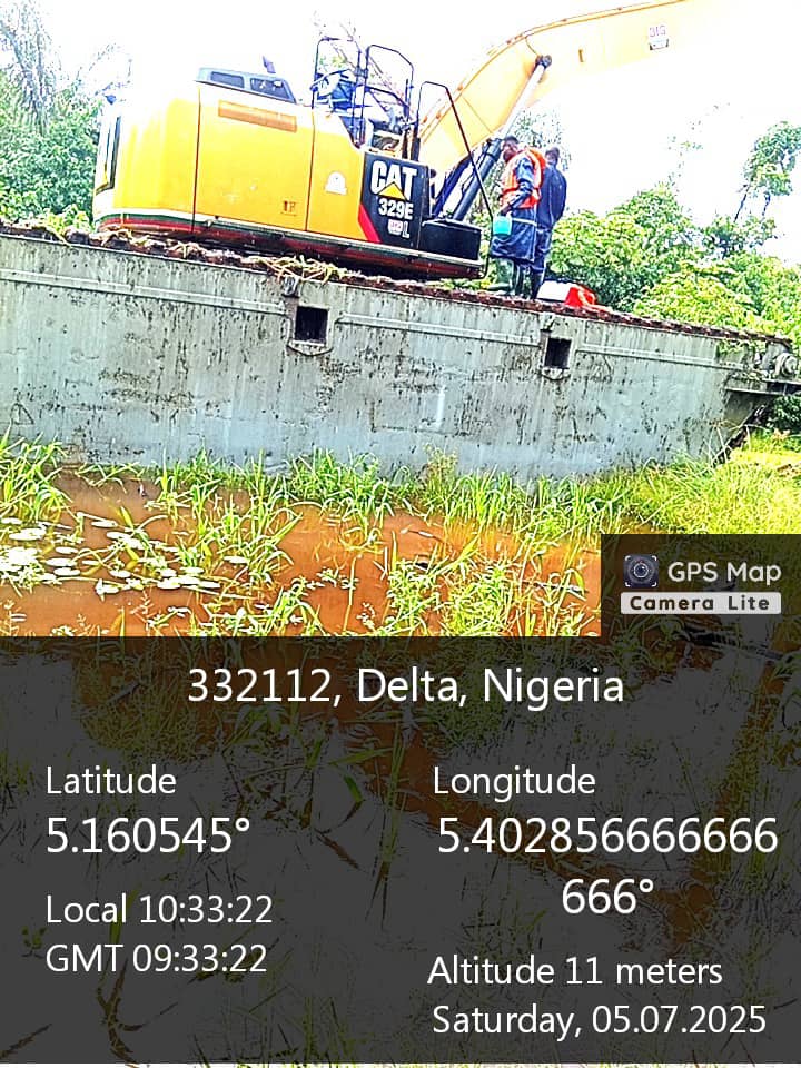 Tracked excavator loaded on a floating platform beside waterlogged ground