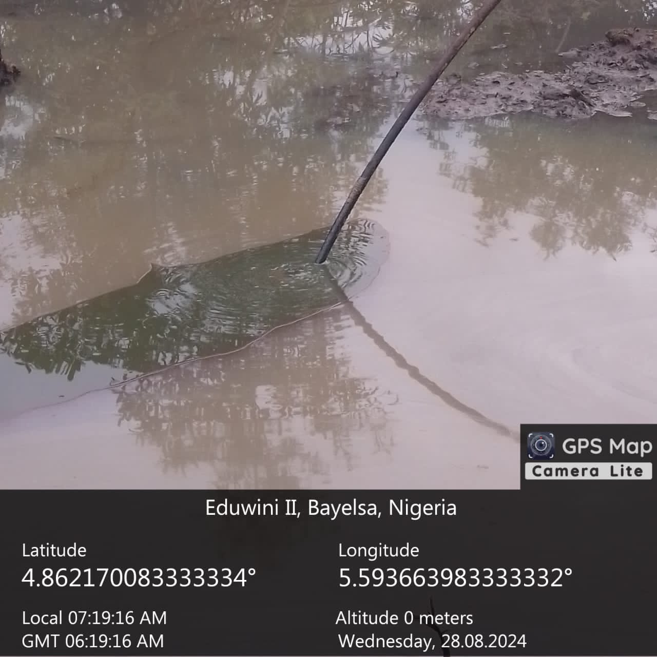 Pipe entering muddy water beside a creek with a GPS location overlay